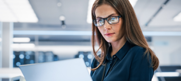 Woman in glasses working on laptop in modern office