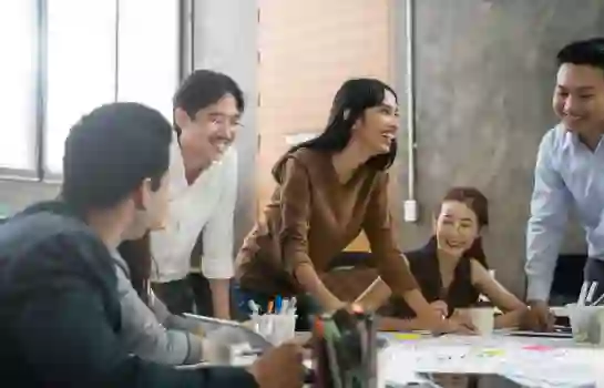 TP team in a collaborative meeting, smiling and discussing ideas around a table.
