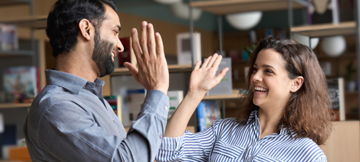 Smiling colleagues giving each other a high five in office